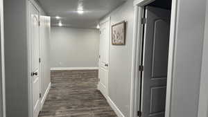 Hall with a textured ceiling and dark wood-type flooring