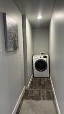 Laundry area with washer / dryer, dark wood finished floors, and a textured ceiling