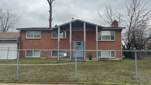 Back of house with a garage, a chimney, and brick siding