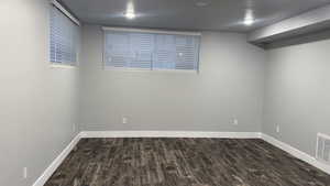 Unfurnished room featuring dark wood-style flooring and baseboards
