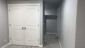 Hall with light colored carpet and baseboards