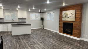 Kitchen featuring white cabinetry, a large fireplace, dark wood-style floors, healthy amount of natural light, and a textured ceiling