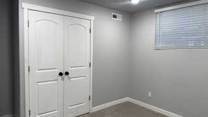 Unfurnished bedroom with dark carpet and a closet