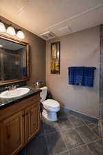 Bathroom with a textured wall, a stall shower, vanity, and a textured ceiling