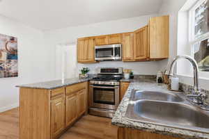Kitchen featuring stainless steel appliances, a peninsula, light stone counters, and healthy amount of natural light