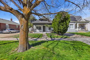 View of front of house featuring covered porch, roof with shingles, solar panels, and a front lawn