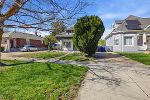 View of front of home with a front yard, concrete driveway, and a porch
