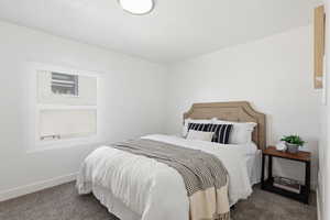Bedroom featuring baseboards and dark carpet