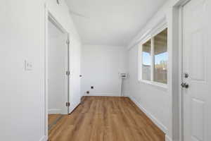 Laundry area with light wood-style floors, washer hookup, and electric dryer hookup