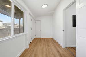 Corridor with light wood finished floors, lofted ceiling, and electric panel