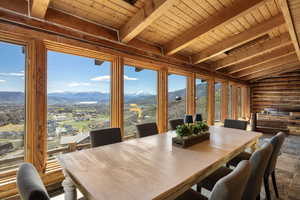 Dining area with log walls, wood ceiling, a mountain view, vaulted ceiling with beams, and stone finish flooring