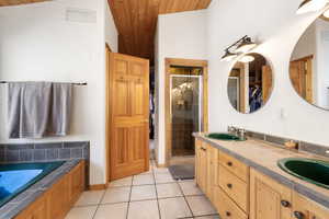 Bathroom featuring double vanity, a shower stall, light tile patterned flooring, a garden tub, and a vaulted wooden ceiling
