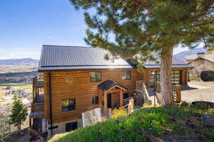 View of front of house featuring a mountain view, log exterior, and a standing seam roof