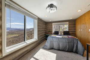 Bedroom with log walls, recessed lighting, light colored carpet, and a mountain view