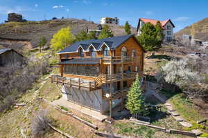 Rear view of property featuring a metal roof, a sunroom, log exterior, and a wooden deck
