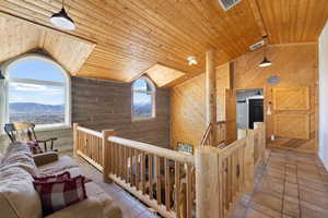 Corridor featuring a mountain view, a high wooden ceiling, an upstairs landing, and log walls