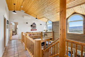 Hall featuring a vaulted wood ceiling, rustic walls, an upstairs landing, and a mountain view