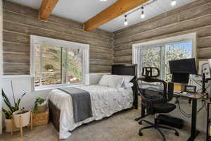 Bedroom with an office area, rustic walls, carpet, and beamed ceiling