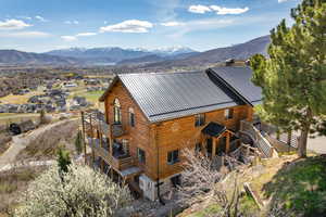 View of home's exterior featuring log siding, a mountain view, and a standing seam roof