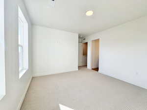 Empty room with light colored carpet and baseboards