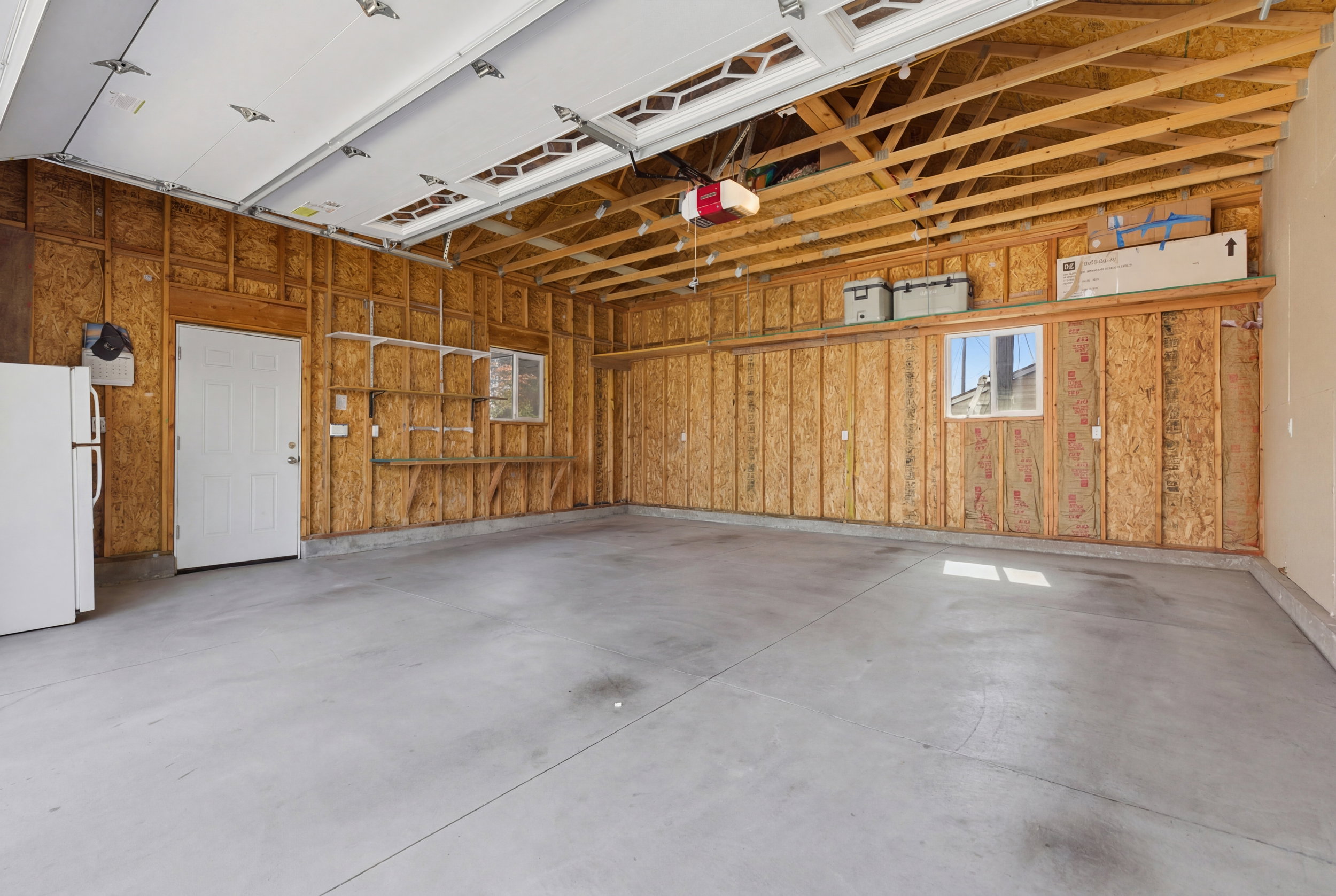 Garage featuring freestanding refrigerator and a garage door opener