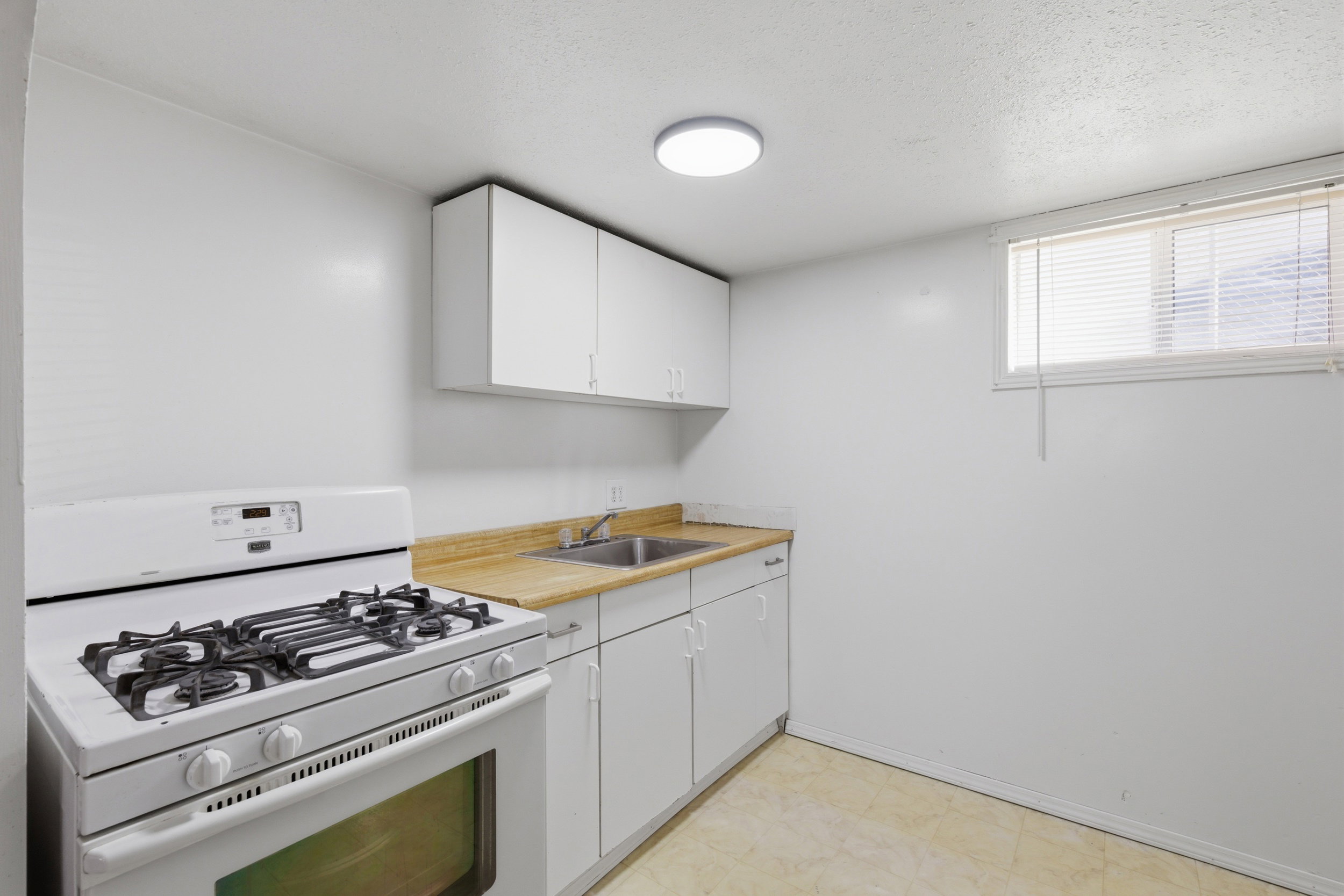 Kitchen featuring gas range gas stove, white cabinets, a textured ceiling, and light floors