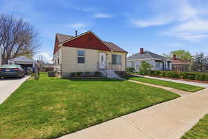 View of front of property with board and batten siding, a front lawn, an outbuilding, and a detached garage