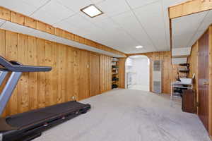 Exercise area featuring a heating unit, carpet floors, arched walkways, and wooden walls