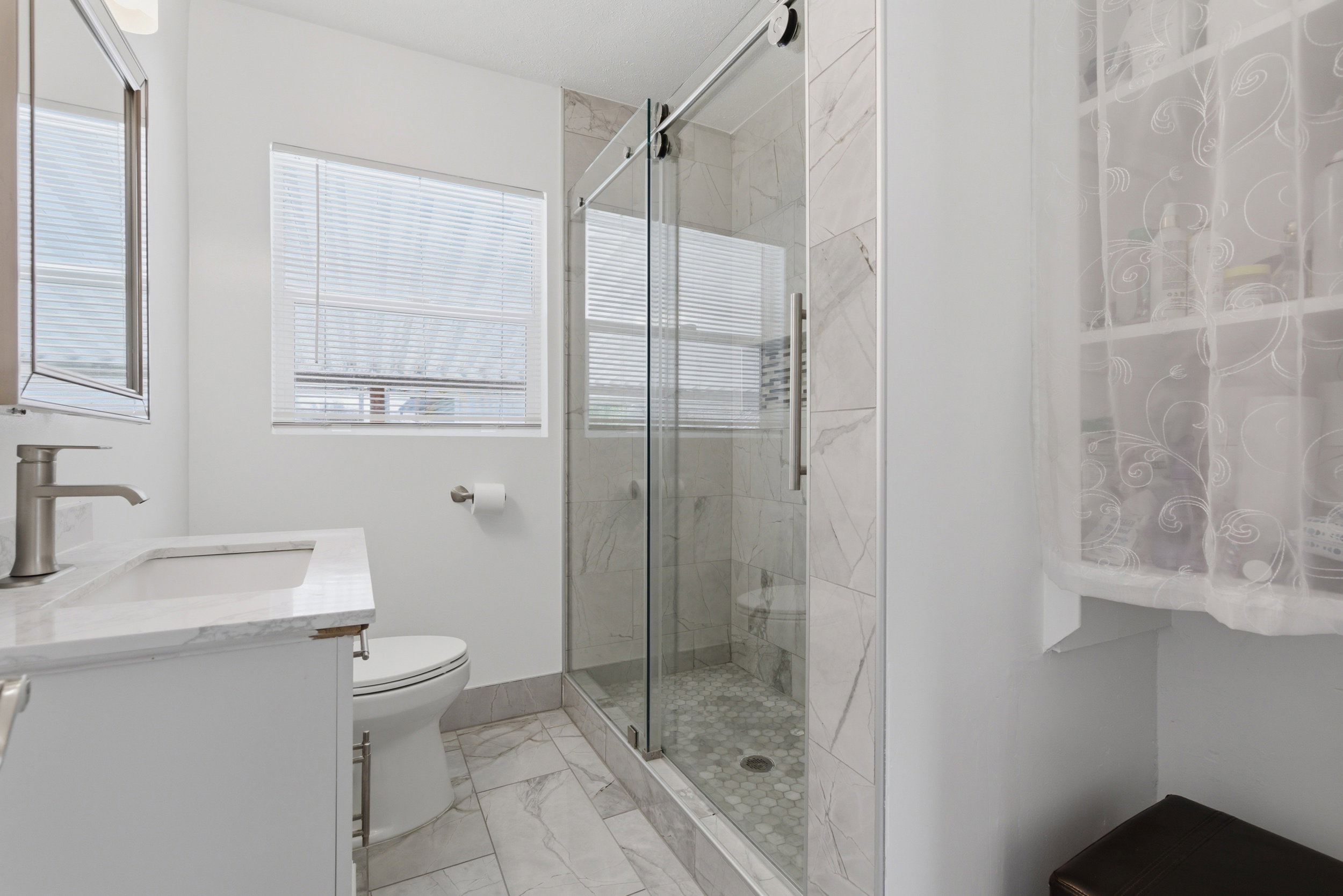 Full bath with a marble finish shower, vanity, and light marble finish floors