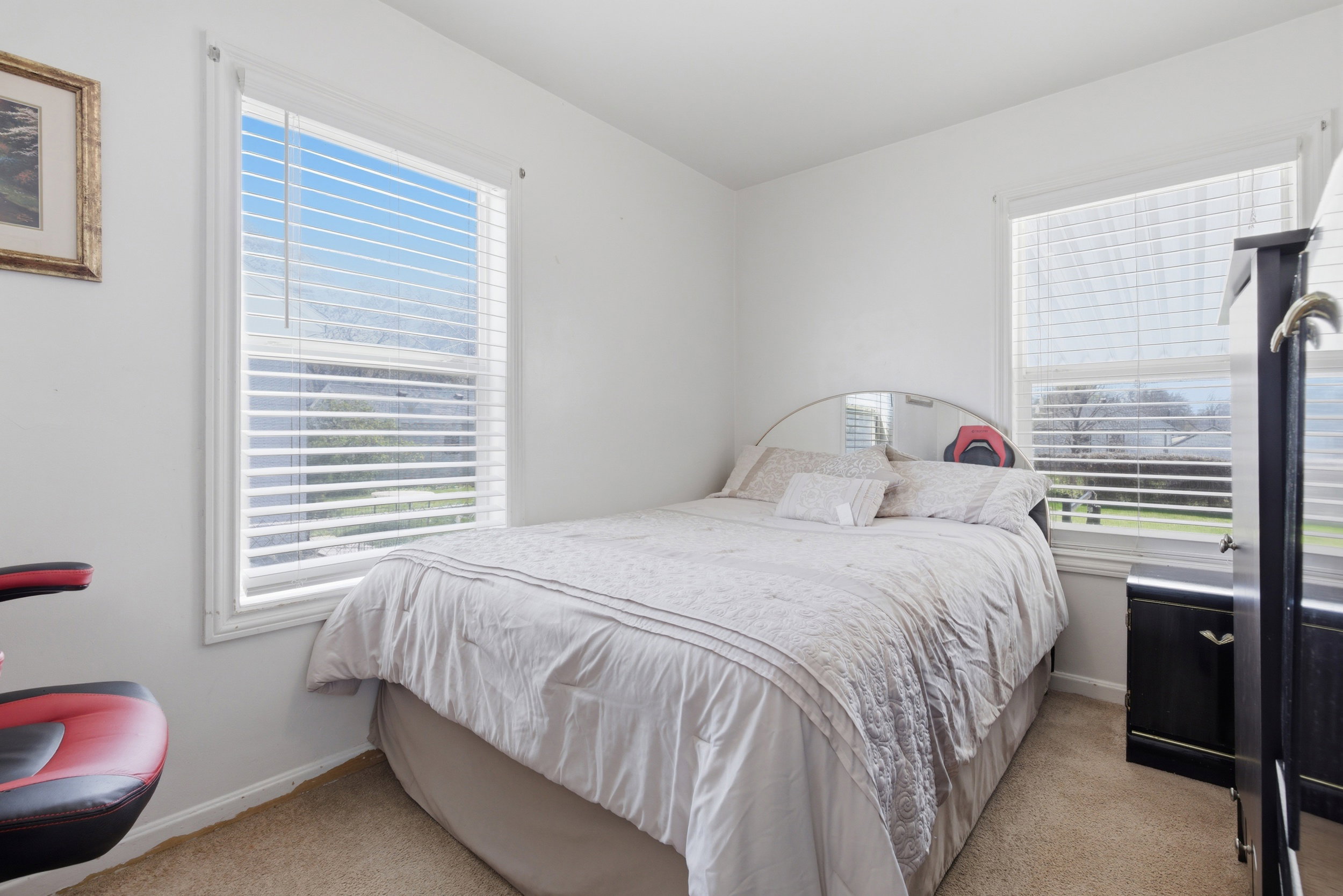 Bedroom with light colored carpet and multiple windows
