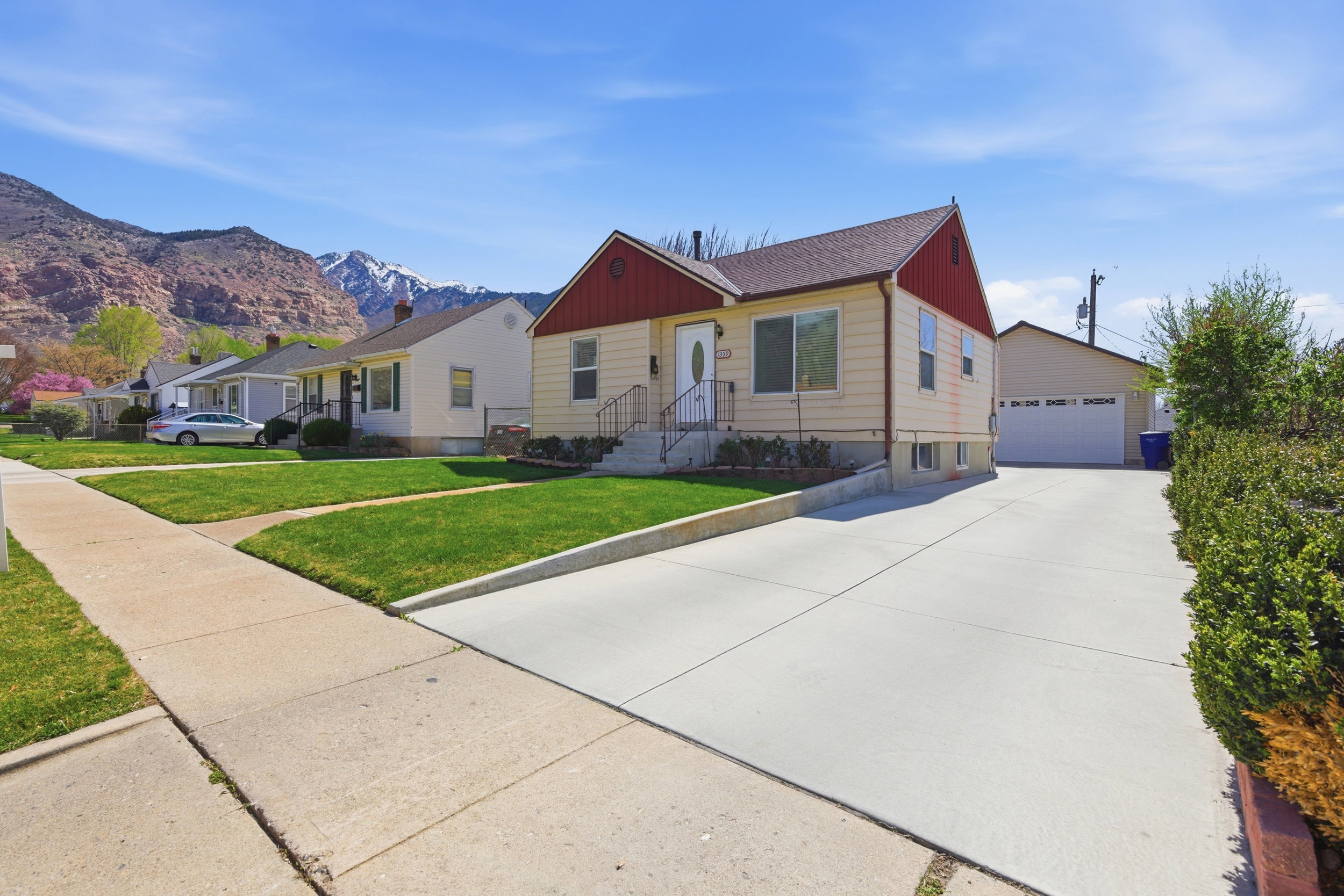 View of front of property featuring a garage, a front lawn, an outdoor structure, and a residential view