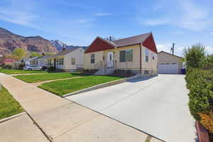 View of front of property featuring a garage, a front lawn, an outdoor structure, and a residential view