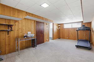 Exercise room with light carpet and wooden walls