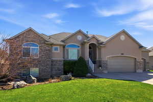 View of front of house featuring a front lawn, a garage, driveway, and stucco siding