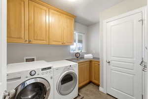 Laundry area with cabinet space, washing machine and dryer, and light tile patterned floors