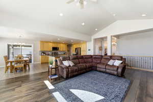 Living room featuring suspended lighting, dark wood-style flooring, and ceiling fan