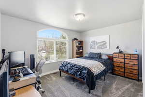 Carpeted bedroom with a desk and baseboards