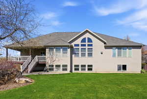 Back of house with stucco siding, a yard, a patio area, and a shingled roof