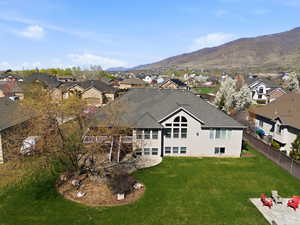 Back of house featuring a residential view, a yard, a patio, and roof with shingles
