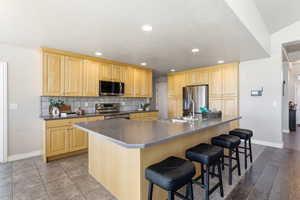 Kitchen featuring dark countertops, light wood finish cabinets, stainless steel appliances, and recessed lighting