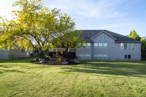 Rear view of property with a yard, stucco siding, a shingled roof, and a wooden deck