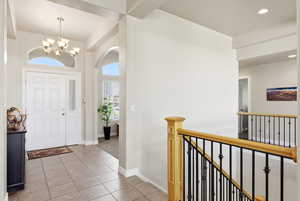 Entryway featuring light tile patterned floors, hanging lights, and arched walkways