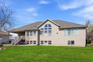 Back of house featuring a patio area, a yard, stucco siding, and a shingled roof