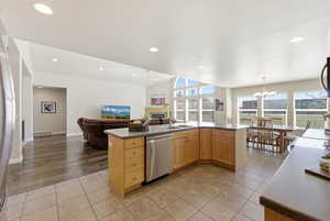 Kitchen with light wood finish cabinetry, open floor plan, light tile patterned flooring, a fireplace, and a chandelier