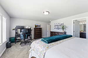 Bedroom with light carpet, an office area, and ensuite bathroom