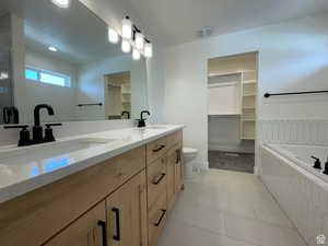Full bathroom featuring a spacious closet, double vanity, light tile patterned floors, a bath, and recessed lighting