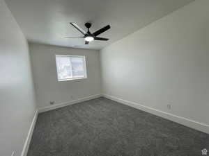 Unfurnished room featuring dark carpet, ceiling fan, and a textured ceiling
