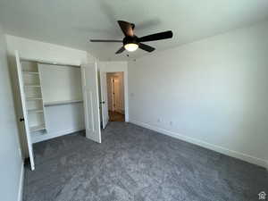 Unfurnished bedroom with dark colored carpet, a ceiling fan, and a closet