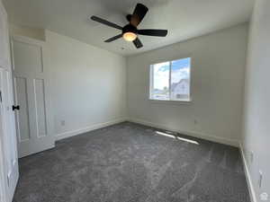 Empty room featuring dark carpet and a ceiling fan