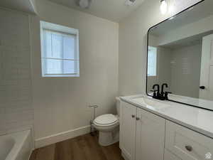 Bathroom featuring vanity, dark wood-type flooring, plenty of natural light, and washtub / shower combination